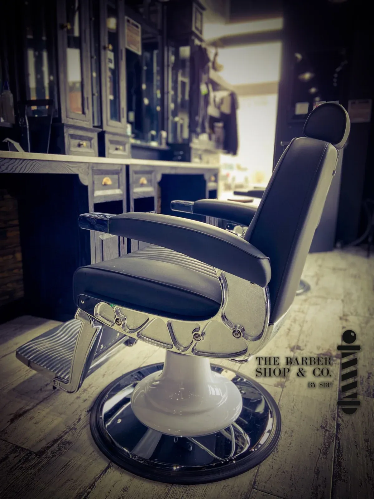 A black vintage barber chair in front of the shop’s black cabinetry.