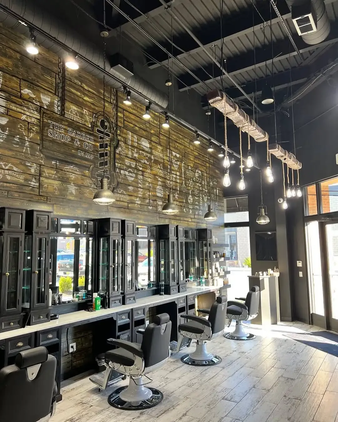 Inside The Barber Shop & Co.: the hand-stenciled reclaimed-wood wall, black cabinetry, vintage chairs and Edison bulbs hanging from a reclaimed beam.